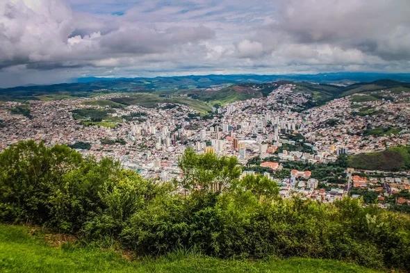 Vista panorâmica da cidade, do ponto de vista do Morro do Cristo. Inúmeras casas e prédios em meio ao verde da natureza.